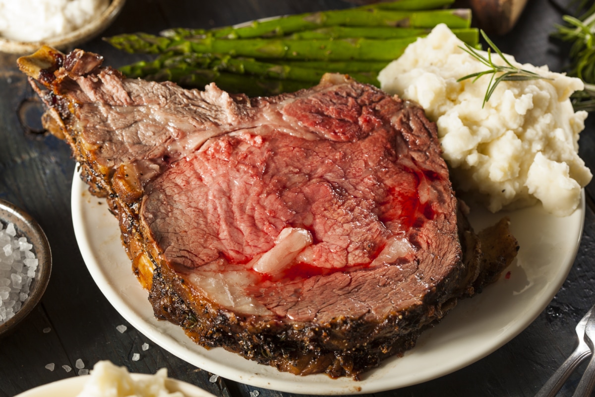 sliced ribeye roast served with potatoed and vegetabls