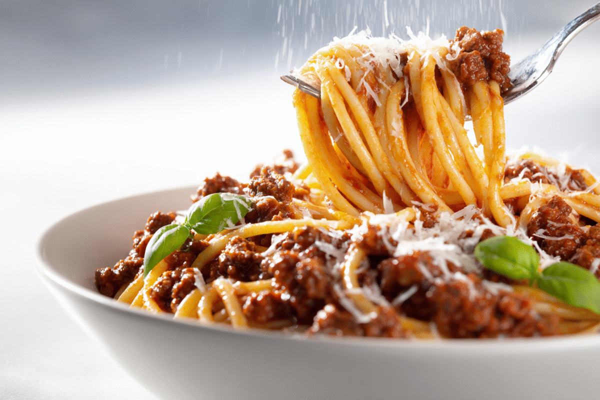 bowl of spaghetti with meat sauce and parmesan with spaghetti twirlled on a spoon