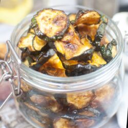 Close up view of air fryer zucchini chips in a mason-type jar with a lid.