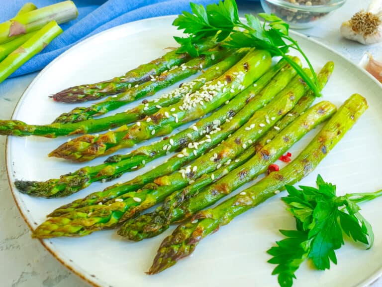 air fryer asparagus on a plate sprinkle with sesame seeds