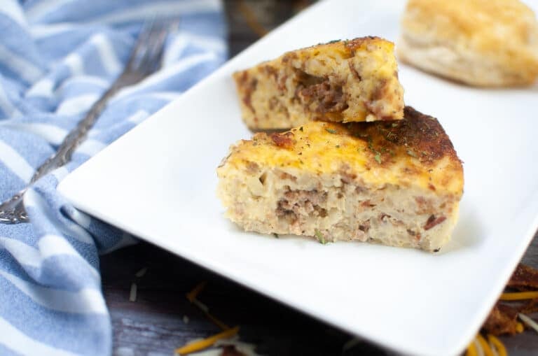 two wedges of air fryer breakfast casserole on a white plate with a biscuit