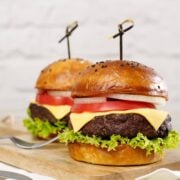 Air fryer burgers from frozen. Two burgers with lettuce, tomato, onion, and cheese on a poppy seed bun.