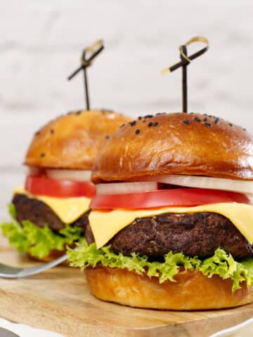 Air fryer burgers from frozen. Two burgers with lettuce, tomato, onion, and cheese on a poppy seed bun.