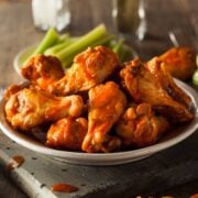 Air fryer chicken wings served in a bowl with celery sticks and blue cheese dressing on the side.