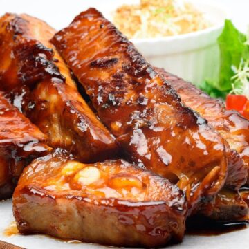 pile of boneless air fryer country style ribs with bbq sauce served with corn and lettuce on the side