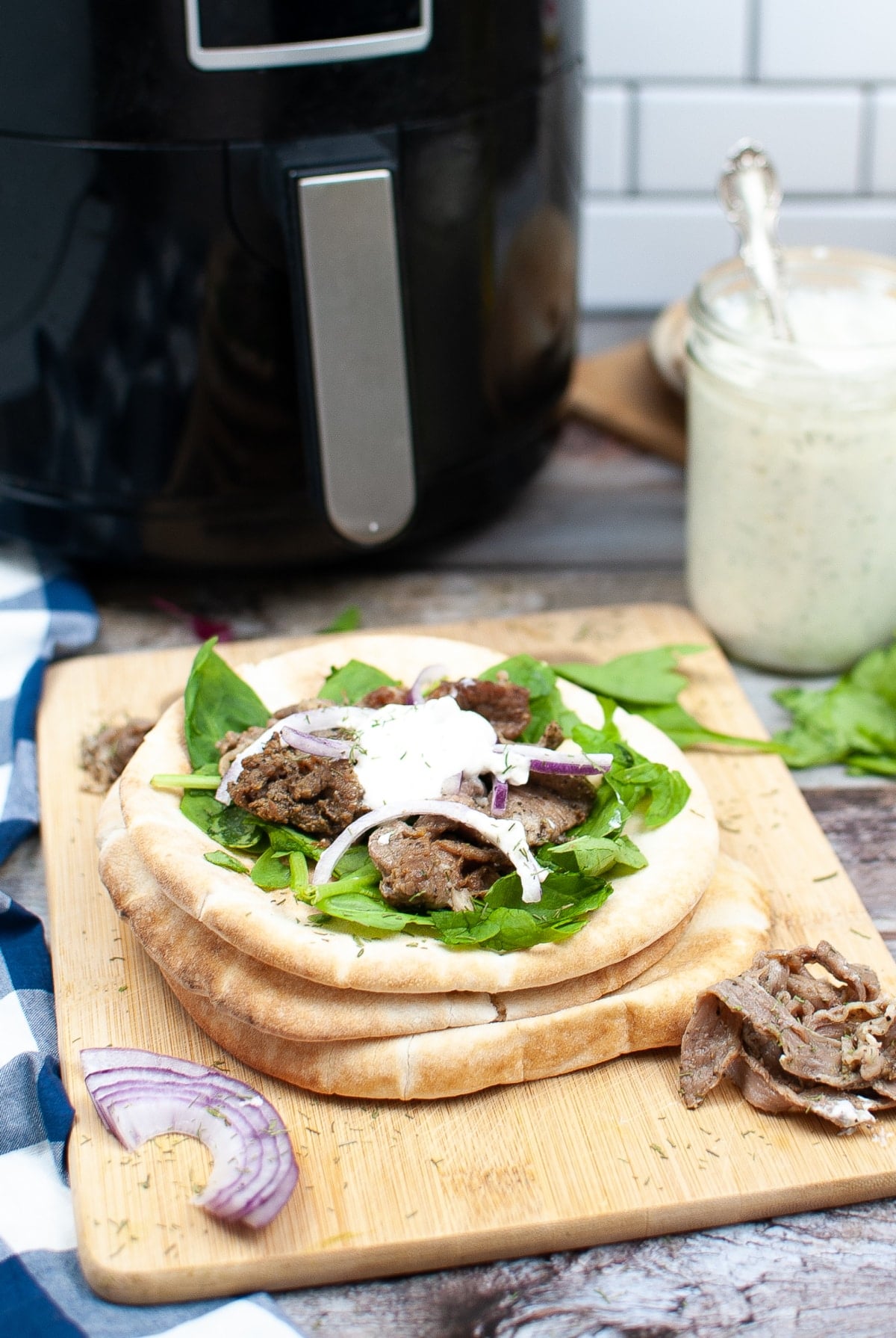 gyro sandwich prepared and on a wooden carving board in front of the air fryer