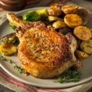 air fryer pork chops served on a plate with roasted potatoes and roasted brussels sprouts