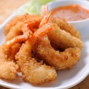 Air fryer shrimp on a white plate with remoulade sauce in a bowl on the side.