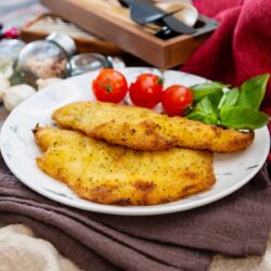 2 pieces of baked flounder with crispy coating on a white plate.