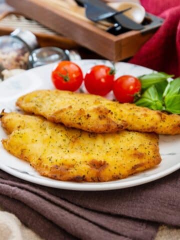 2 pieces of baked flounder with crispy coating on a white plate.