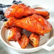 Baked bbq chicken legs on a white platter.