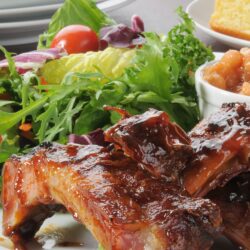 Carved BBQ ribs are slathered in a rich BBQ sauce.