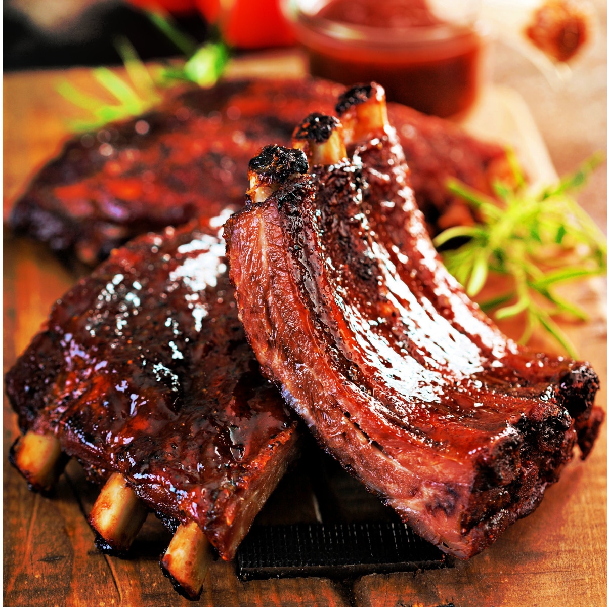 close up of beef back ribs recipe with ribs cut into 3 ribs portions. ribs are beautifully caramelized in a bbq sauce