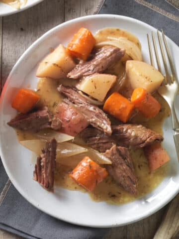 Beef chuck roast cross rib roast served with potatoes and carrrots.