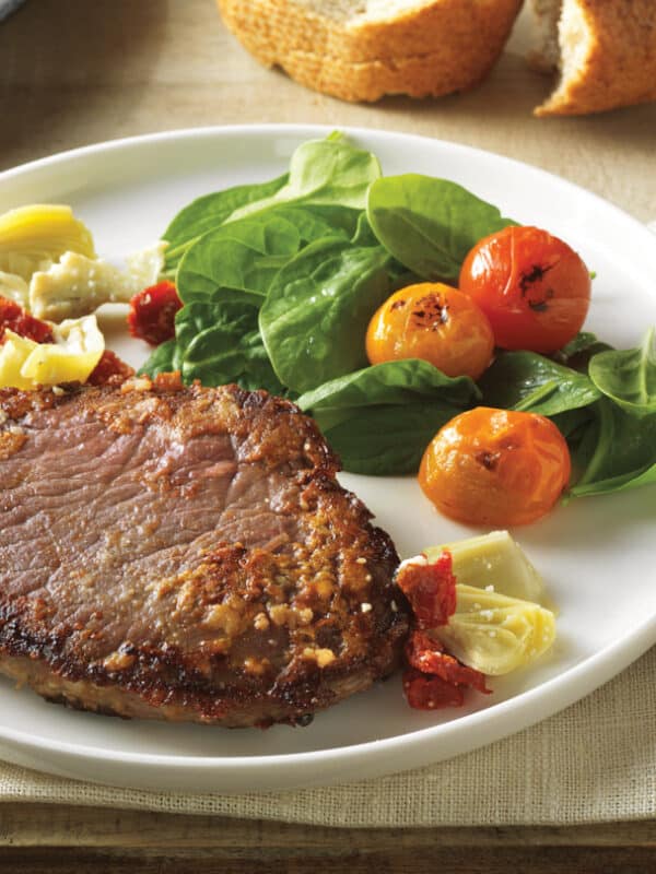 plate of beef chuck steak with vegetables on the side