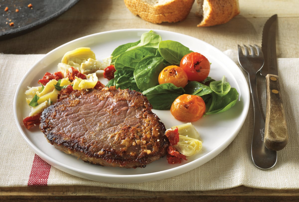 plate of beef chuck steak with vegetables on the side