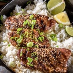 beef flanken short ribs, garnished with green onions and toasted sesame seeds, on a bed of white rice