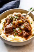 Beef Tips and Gravy beef tips in gravy served over mashed potatoes in a bowl