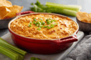 buffalo chicken dip in an oven baker with celery and chips on the side