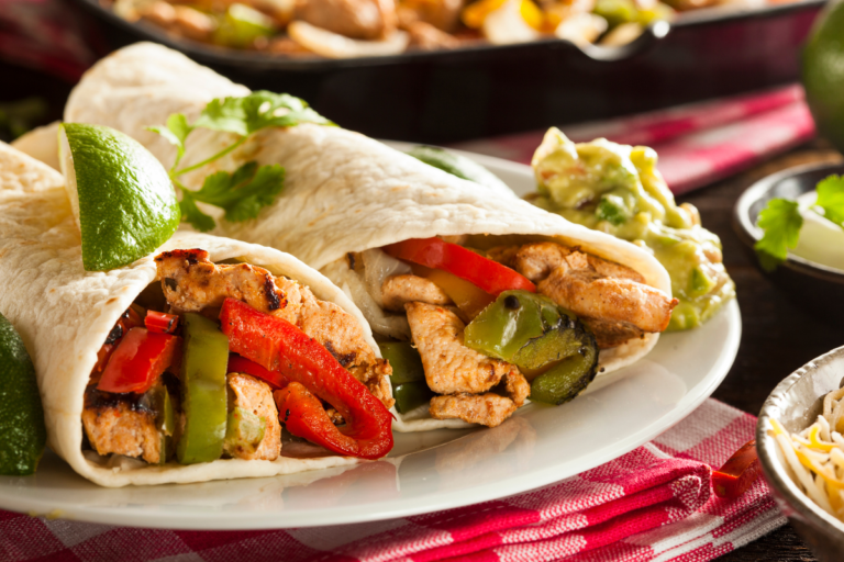 chicken fajitas served wtih lime wedges and guacamole