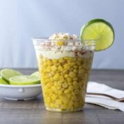 Mexican esquites served in a clear cup garnished with lime