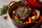 red enameled Dutch oven with beef chuck roast and veggies