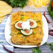 platter of 4 green chili enchiladas on white with scattered ingredients on the table