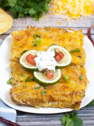 platter of 4 green chili enchiladas on white with scattered ingredients on the table