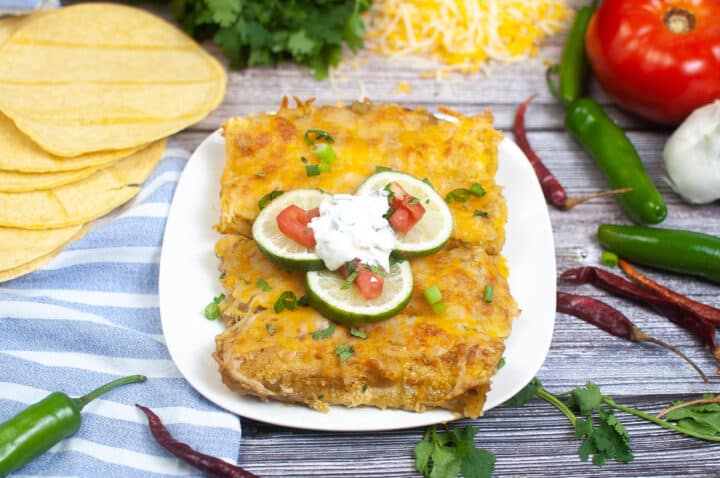 platter of 4 green chili enchiladas on white with scattered ingredients on the table