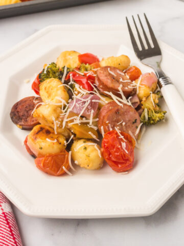 showing how to cook sausage in the oven on a sheet pan with veggies and served on a plate