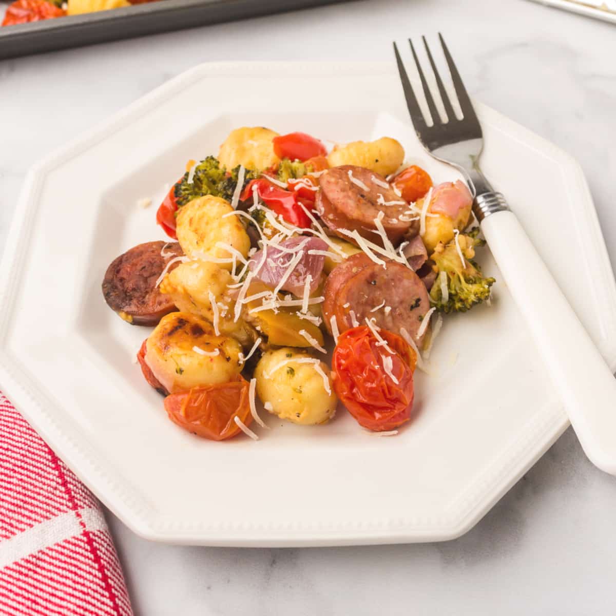 showing how to cook sausage in the oven on a sheet pan with veggies and served on a plate