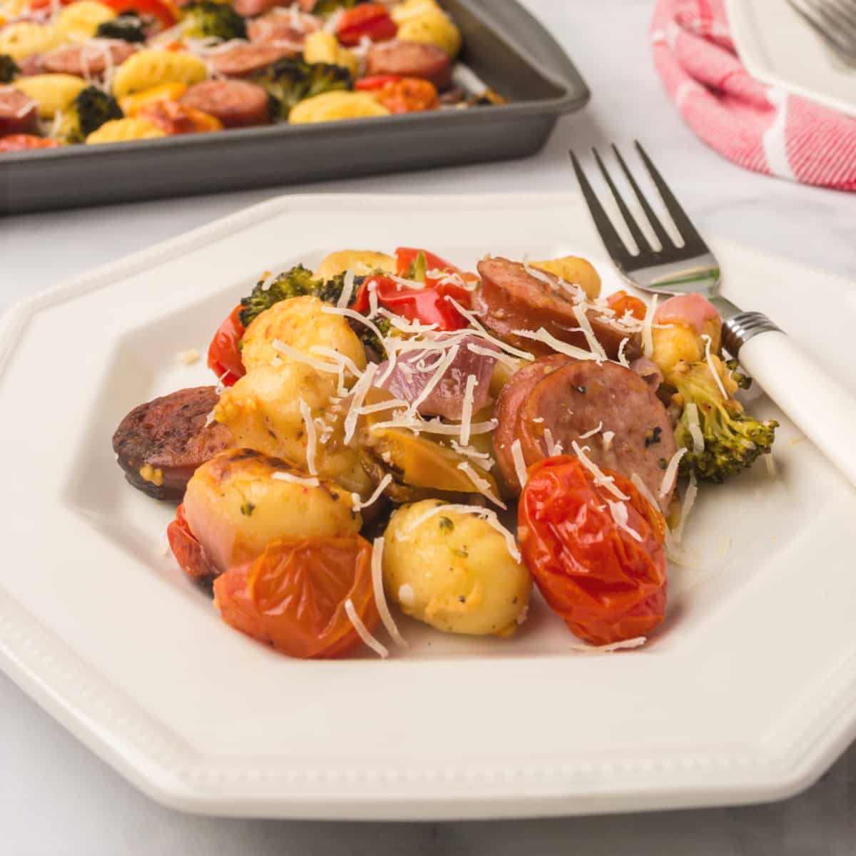 sausage and vegetable sheet pan dinner served on a white plate