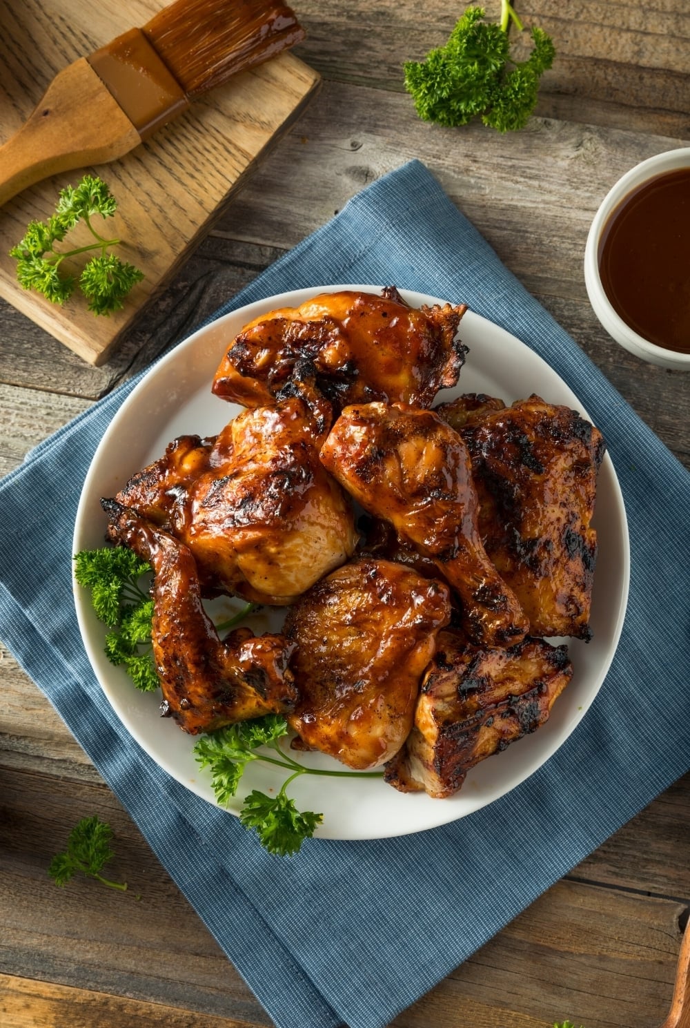 Instant Pot BBQ Chicken ready to eat. Served with extra BBQ sauce on the side and garnished with herbs