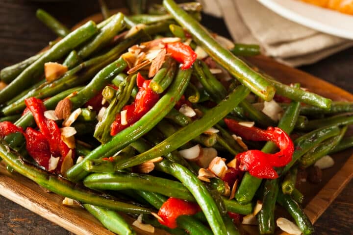 instant pot green beans with red pepper and nuts on a square plate