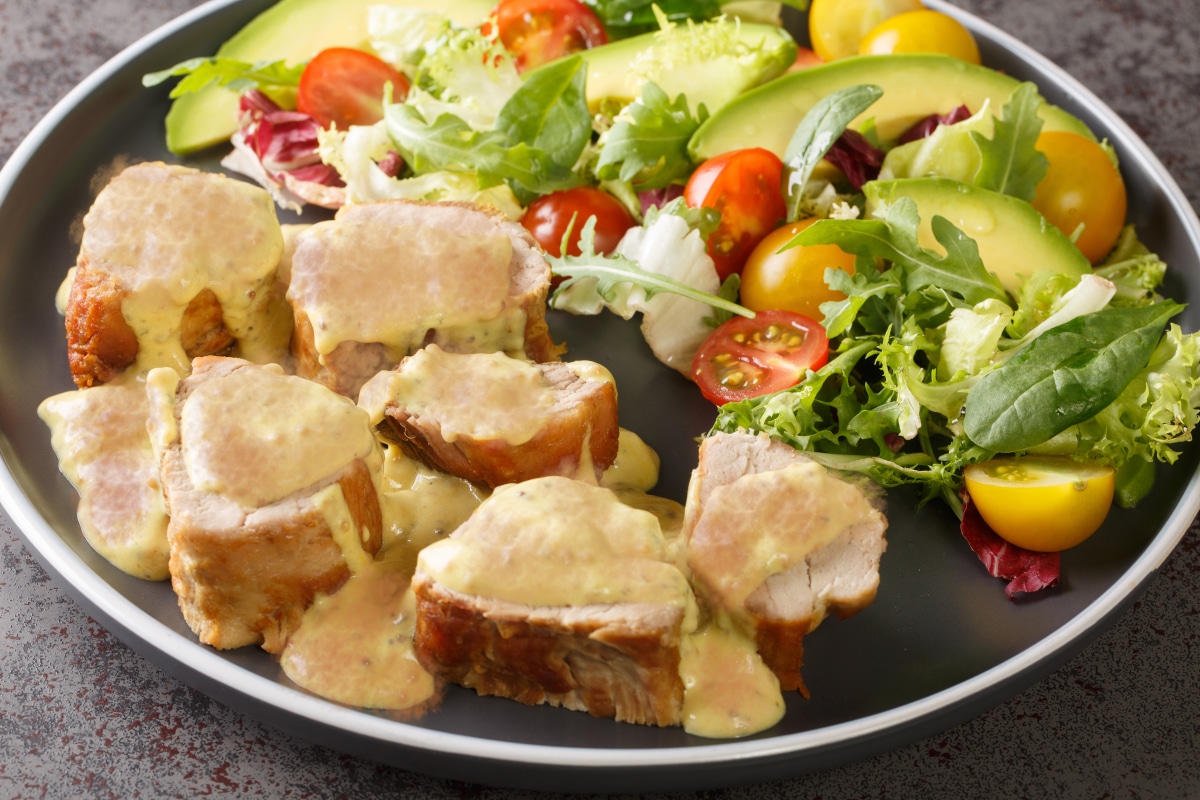 Sliced Pork Tenderloin Drizzled with sauce and a side salad