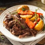 closeup view of Instant Pot pot roast with carrots and potatoes served on a white plate