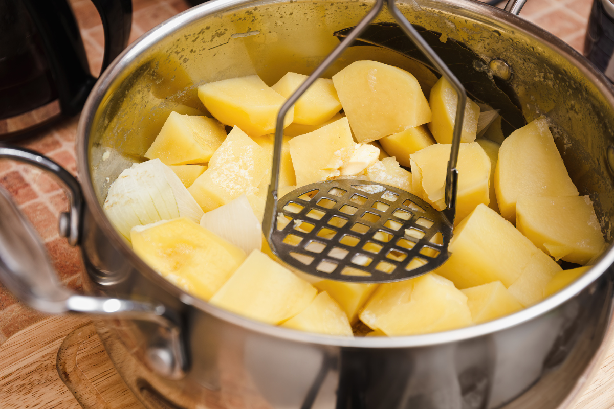 mashing boiled potatoes in a pot for shepherds pie topping