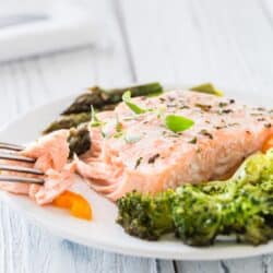flaky oven baked salmon on fork with vegetables