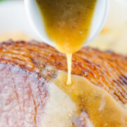 Pouring pineapple brown sugar glaze over spiral cut ham.