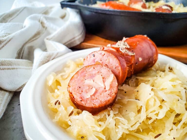 closeup of sliced cooked polish sausage served on seasoned sauerkraut