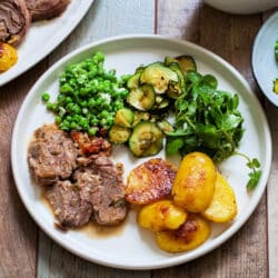 roast leg pf lamb sliced served with potatoes and vegetables