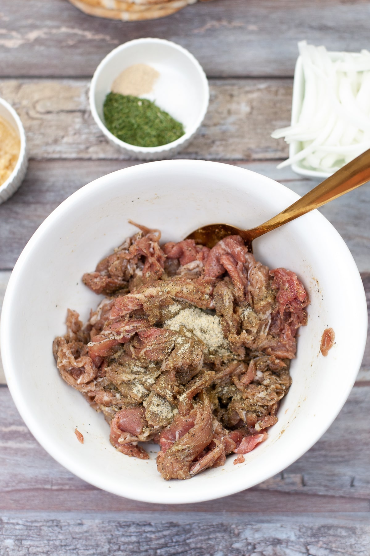 Greek seasoned shaved beef in a bowl marinating