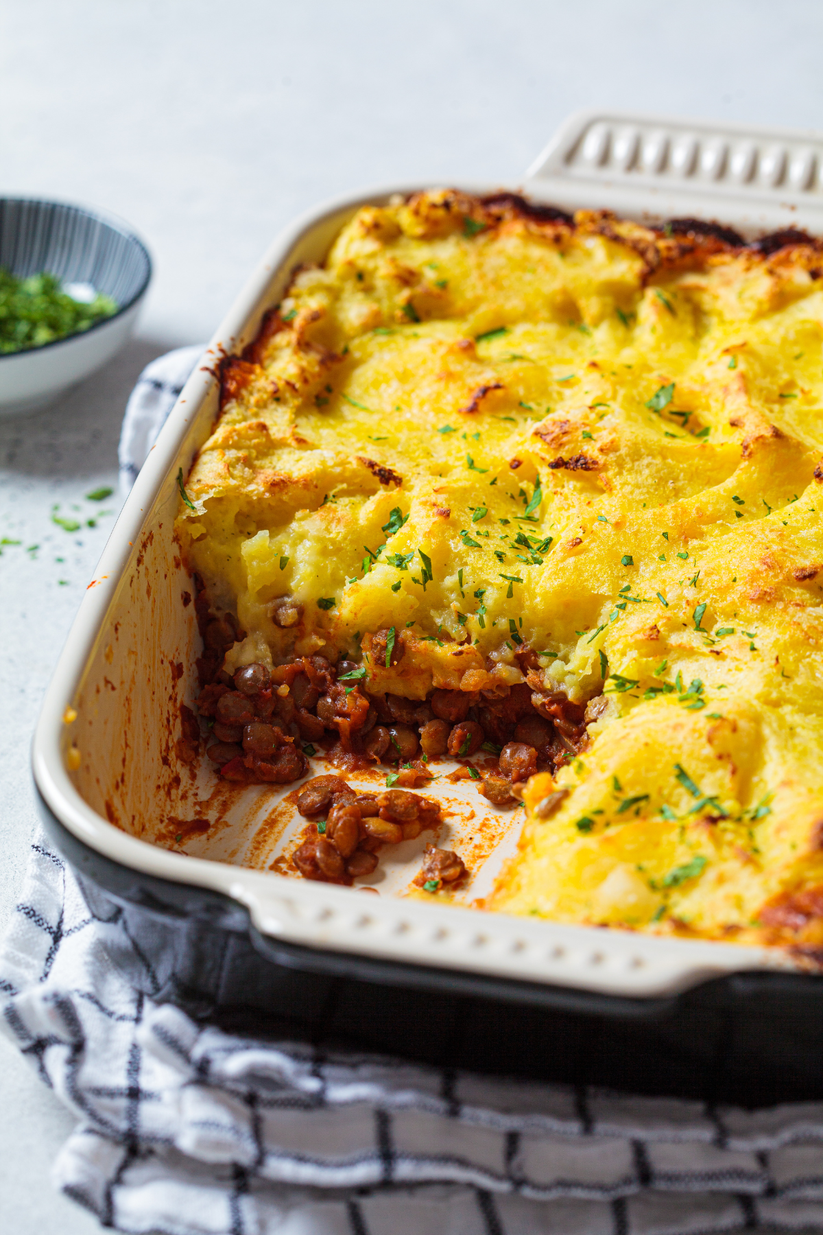 baked shepherd's pie in a rectangular casserole dish with a serving removed