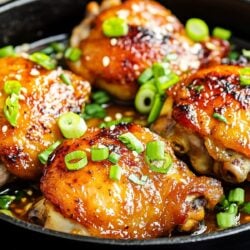 miso butter chicken thighs in a skillet and garnished with sliced scallions