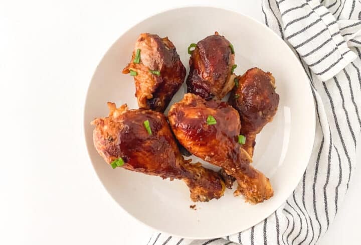 Slow cooker bbq chicken legs on a white plate - landscape view.
