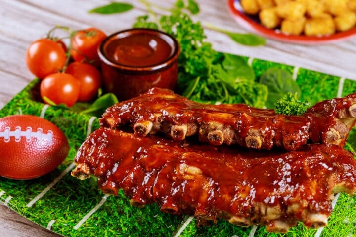 slow cooker BBQ rib racks arranged on a football turf themed platter