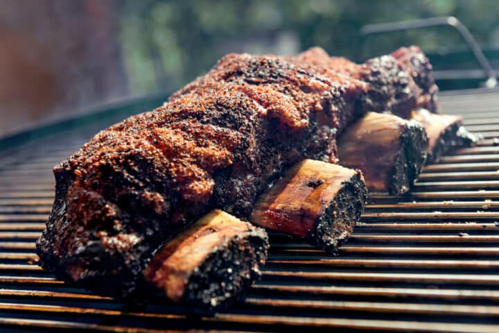 beef short ribs on a grate for smoking or grilling