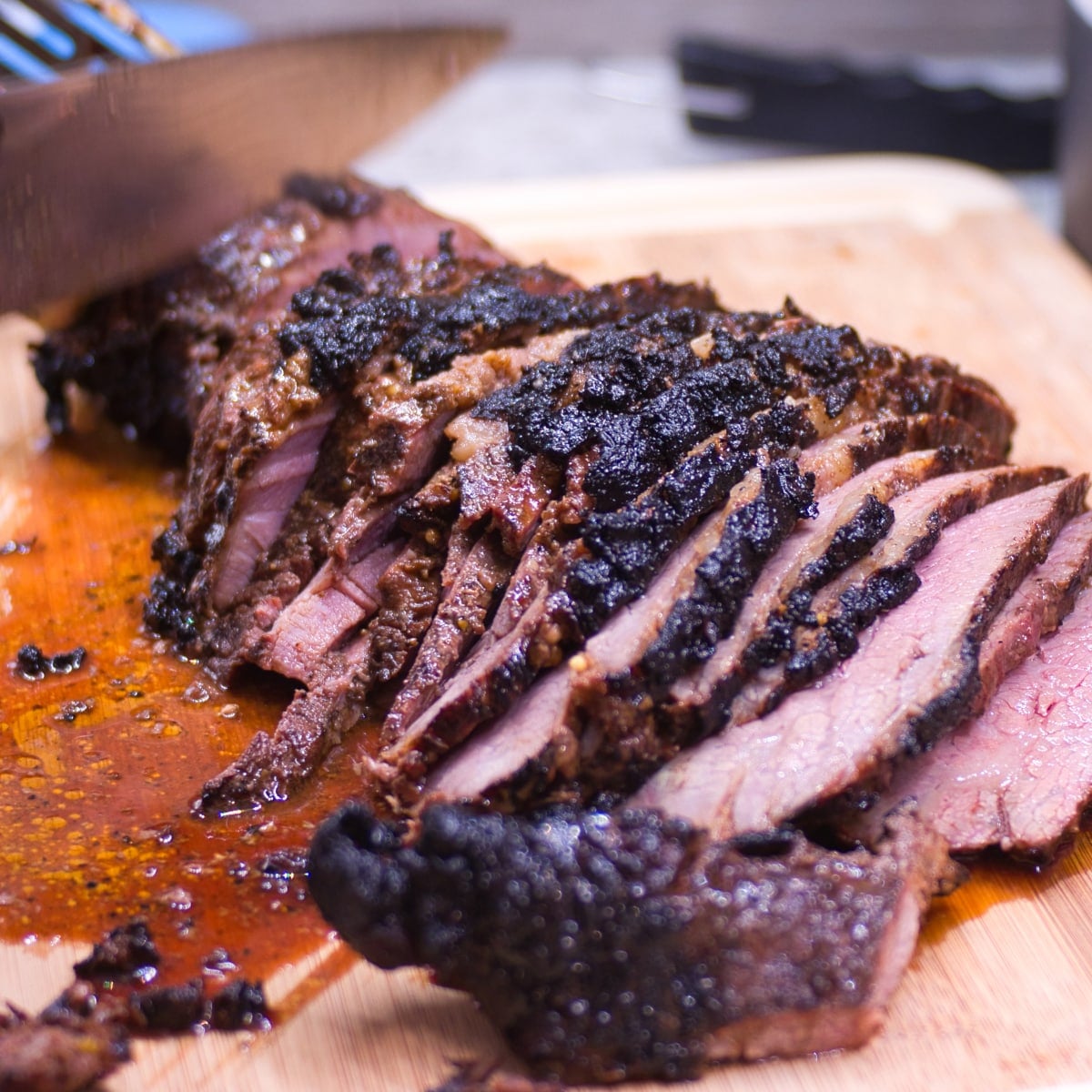 smoked tri tip sliced on a cutting board showing tender inside and a nice bark outside.