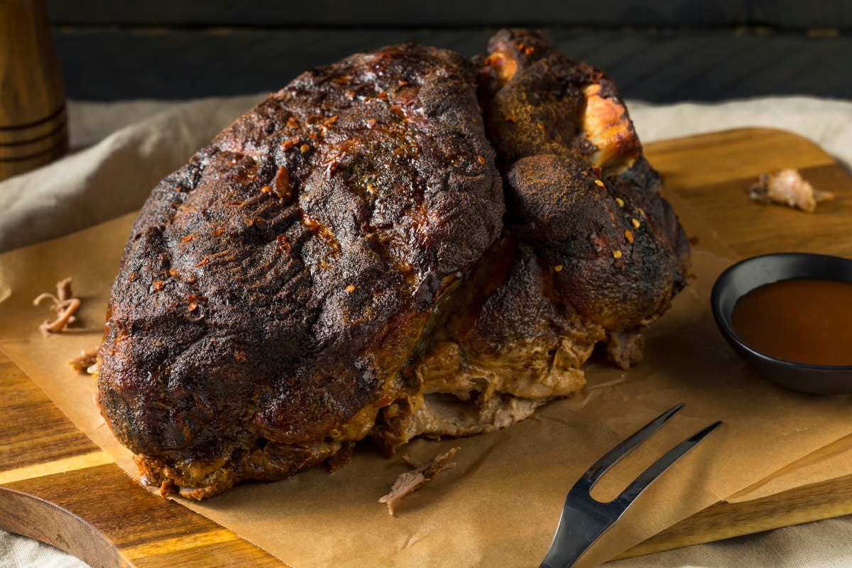whole smoked chuck roast on a wooden cutting board ready for carving or shredding