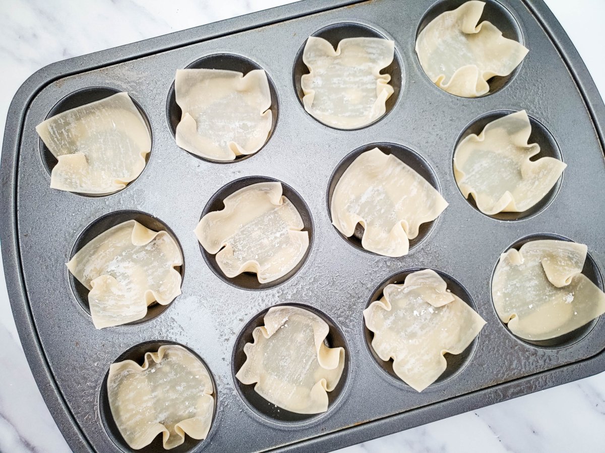 wonton wrappers pressed down into muffin cups before cooking